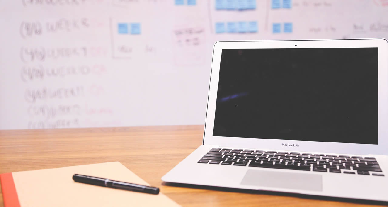 Scrivania con laptop aperto e quaderno per gli appunti